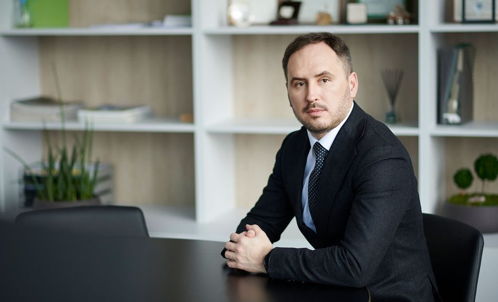 Lietuvos centrinės kredito unijos administracijos vadovas ir valdybos pirmininkas biuro aplinko sėdi prie stalo ir žvelgia į kamerą.
