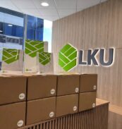Dėžės biure su dovanomis vaikams projekte "Vaikų svajonės", LKU kredito unijų grupės logotipas ant sienos